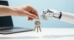 A human hand passes a ring of plain silver keys to a white robotic hand above a bright white desk, a laptop out of focus behind them