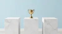 Three white marble pedestals of almost equal height in a bright gallery, a small brass trophy on the middle one