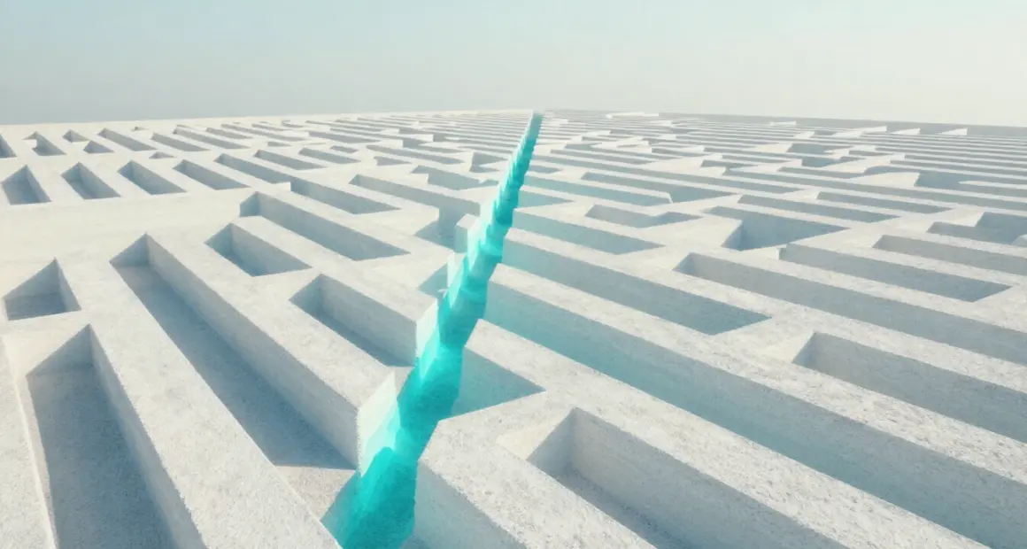 Aerial view of a large white maze with one straight turquoise path cutting diagonally through its walls