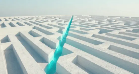 Aerial view of a large white maze with one straight turquoise path cutting diagonally through its walls