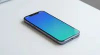 A smartphone lying on a bright white desk, its blank screen glowing in blue and turquoise
